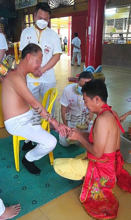 东：关丹斗母宫坛前组乩童办坛，用拔罐疗法，为善信改善病况。