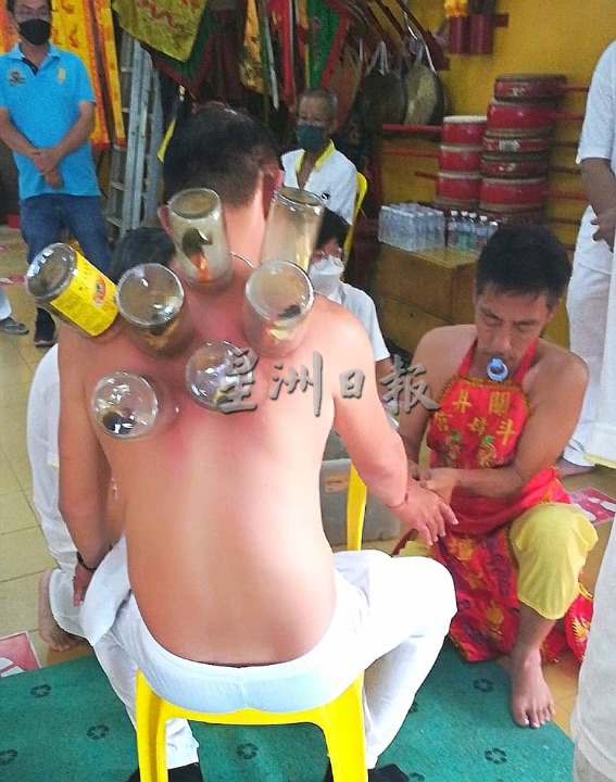 东：关丹斗母宫坛前组乩童办坛，用拔罐疗法，为善信改善病况。