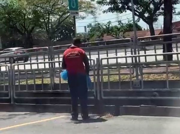 清洁人员把落叶集中到排水口前,再扫入水沟内。(视频截图)