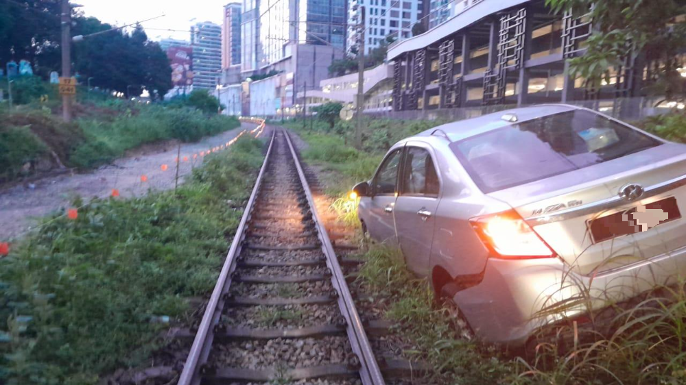 轿车“跌入”电动火车轨道旁 服务一度中断