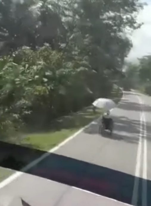 （大北马）男子撑伞坐轮椅在大路上悠悠地行驶